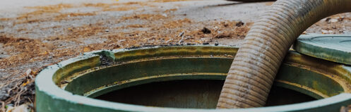 Pumping septic tanks from backyard tank in rural Wisconsin area, Pipe in the drainage hole.